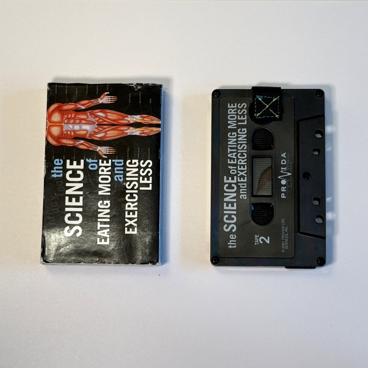 Black The Science of Eating More and Exercising Less cassette wallet with a black pull tab and original sleeve