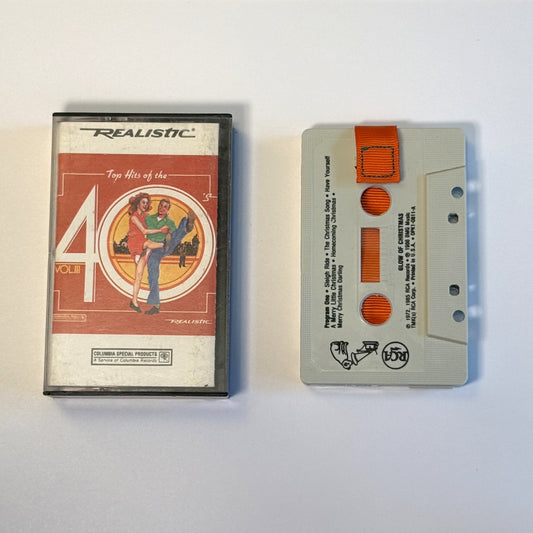 Glow of Christmas gray cassette wallet with an orange pull tab beside a Realistic Top Hits of the 40s case