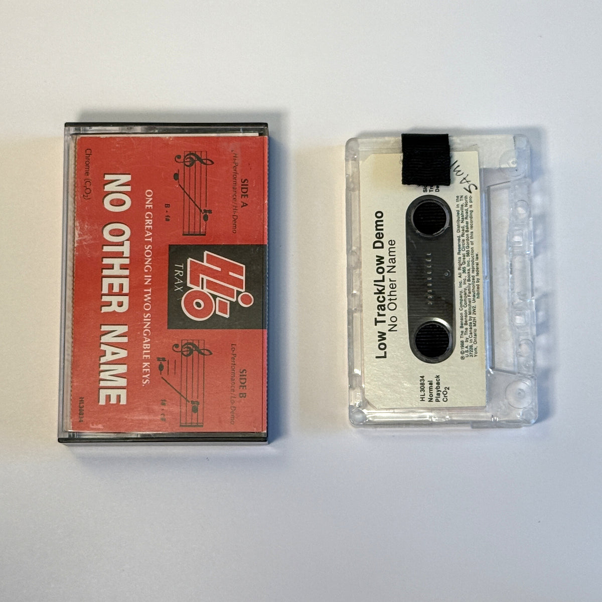 No Other Name low-track demo clear cassette wallet with a black pull tab beside the red Hi-Lo Trax case