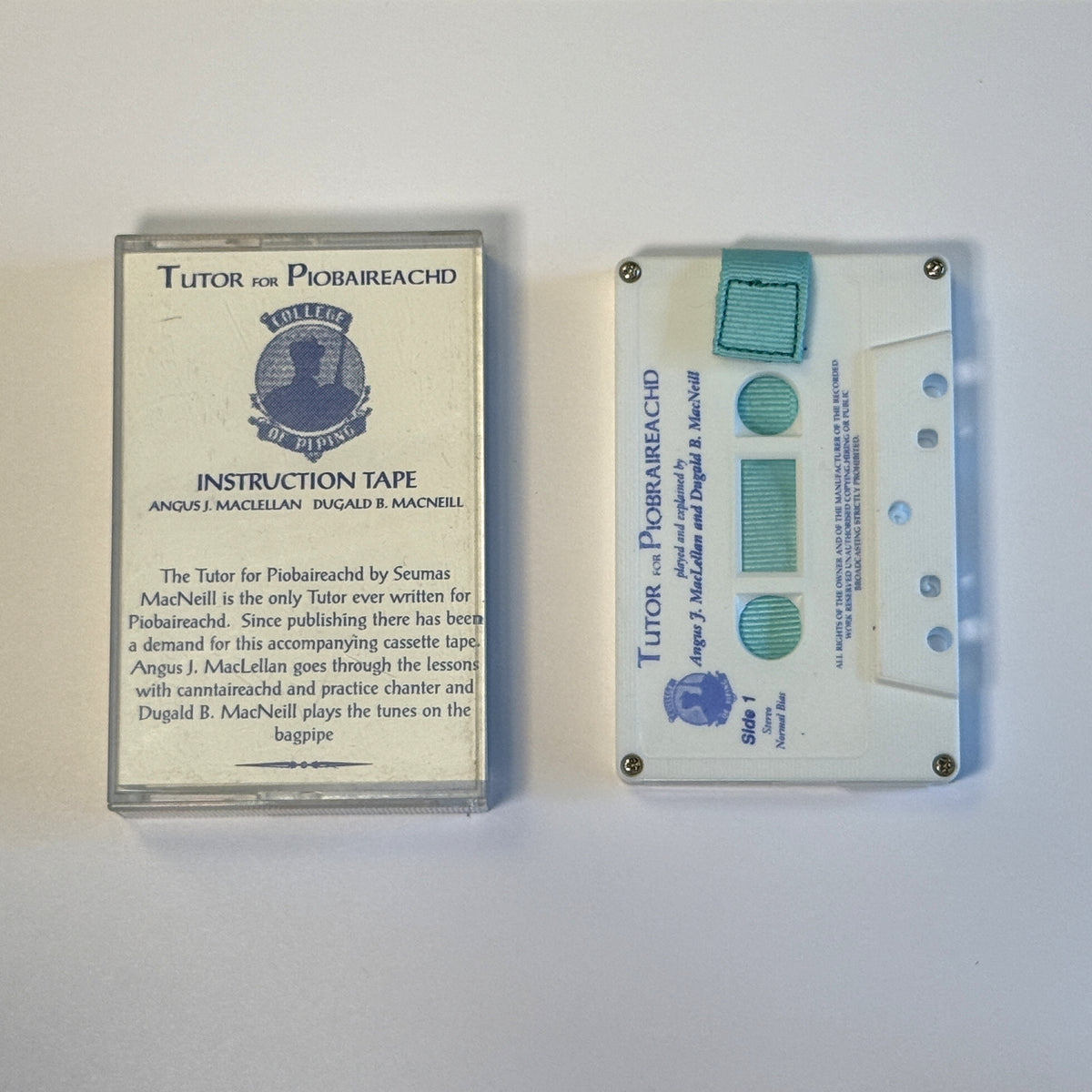 Tutor for Piobaireachd white cassette wallet with aqua pull tab beside the original instruction tape case